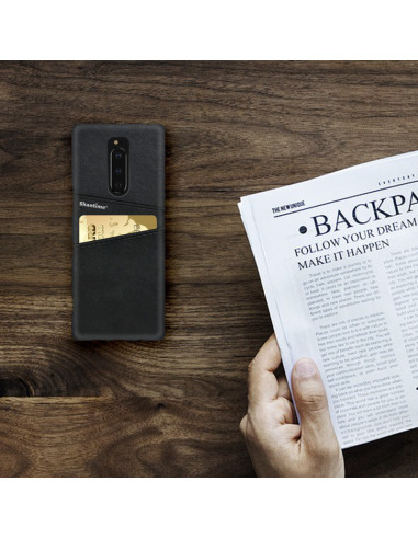 Svart Sony Xperia 1 skal med korthållare, placerat på ett bord med en tidning och en hand i bild