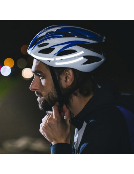 Man med cykelhjälm utrustad med reflexklistermärken i mörk miljö