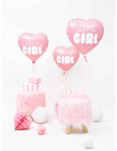 Två rosa folieballonger i hjärtform med texten It's a Girl, placerade med dekorationer