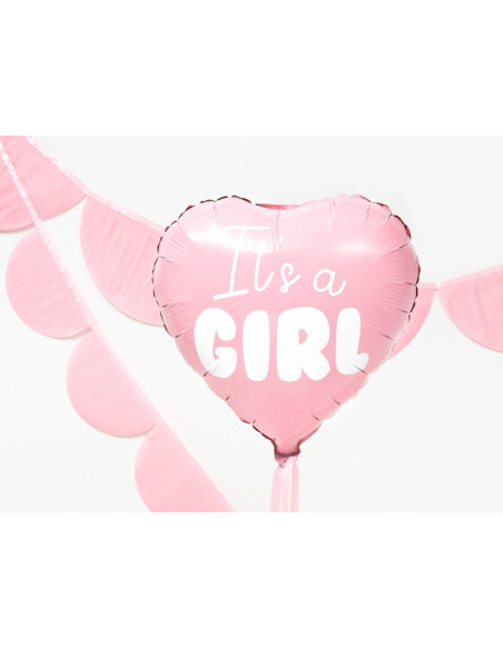 Folieballong i hjärtform med texten It's a Girl, hängande med dekorationer i bakgrunden