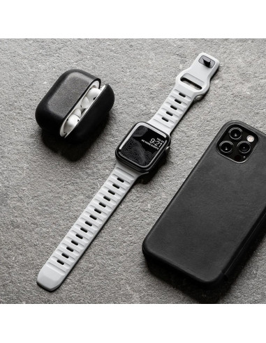 Ljusgrått Titan's Grip armband liggande bredvid en iPhone och hörlurar